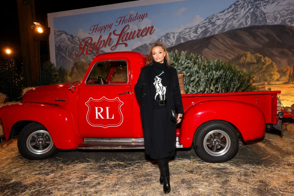 Woman standing beside a red Ralph Lauren holiday truck at a branded experiential pop-up, representing the backstage loyalty program approach to immersive brand activation.